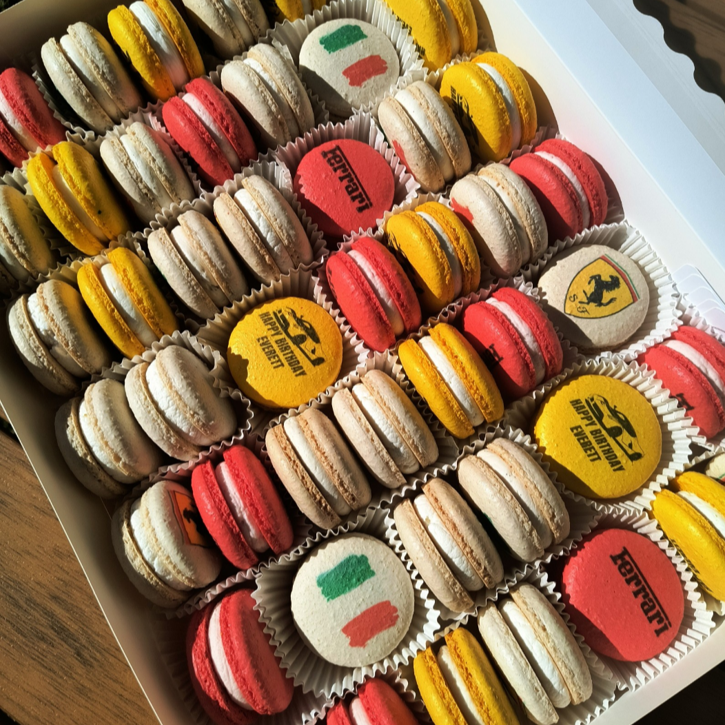 Box of Ferrari-themed macarons with colorful designs.